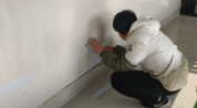 男孩抠坏教室墙面 家长来校修补