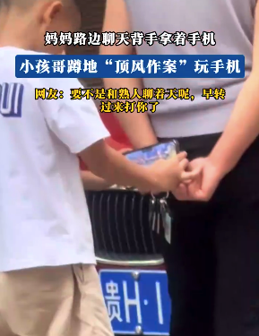 妈妈路边聊天背手拿着手机 小孩哥蹲地“顶风作案”玩手机