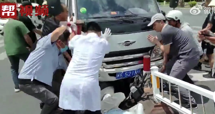 女生的腿被车压住 路人合力抬车营救