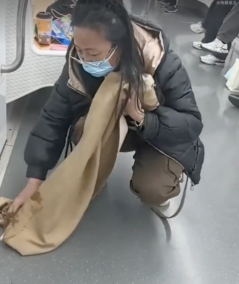 女子在地铁上用围巾擦拭污渍