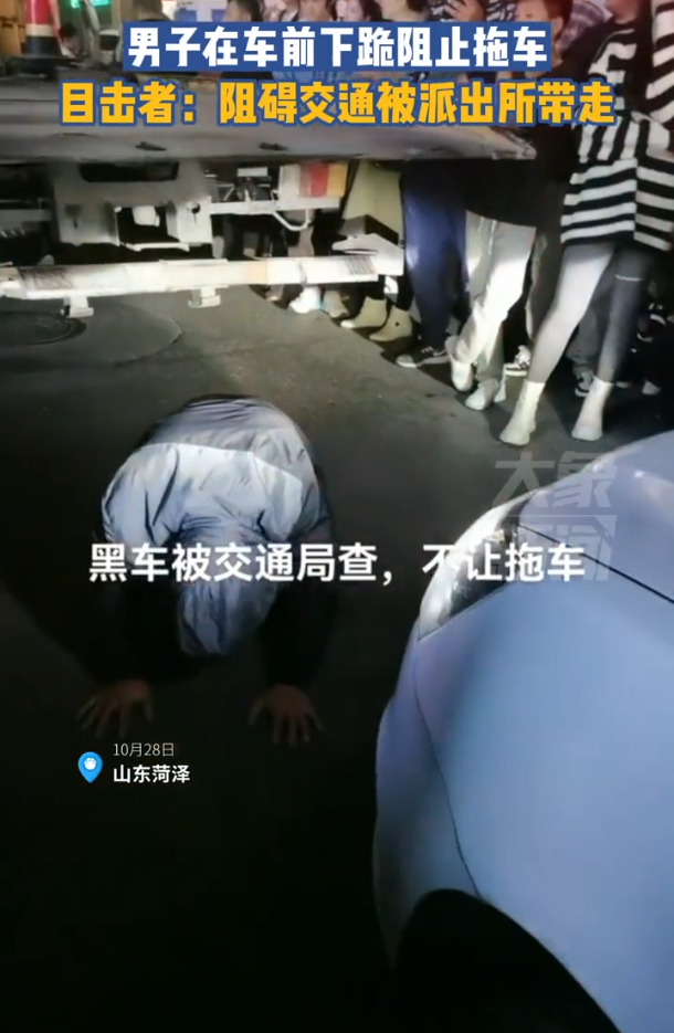 男子在车前下跪阻止拖车