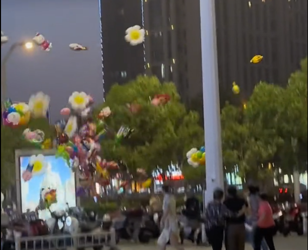老人卖气球遭遇狂风 气球被吹飞，多名路人上前帮助，目击者：风很大，觉得气球飞向天空时很美