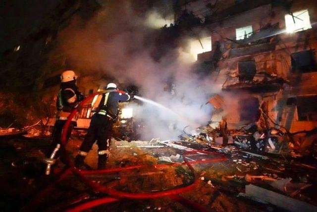 25日，基辅遭受火箭袭击后，消防员用软管冲洗一栋受损建筑前燃烧的碎片。图源：美联社