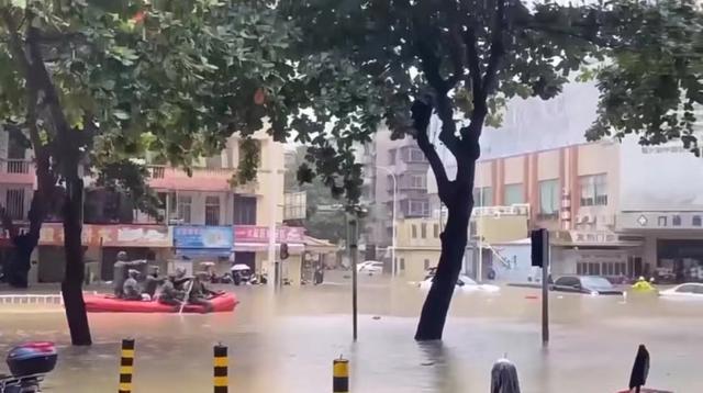 广东湛江暴雨致部分路段车泡水 市民推车涉水前行
