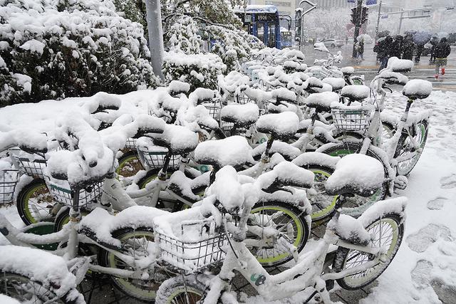 2024年11月27日，韩国首尔，一些被雪覆盖的自行车停放在地铁站附近。视觉中国 图