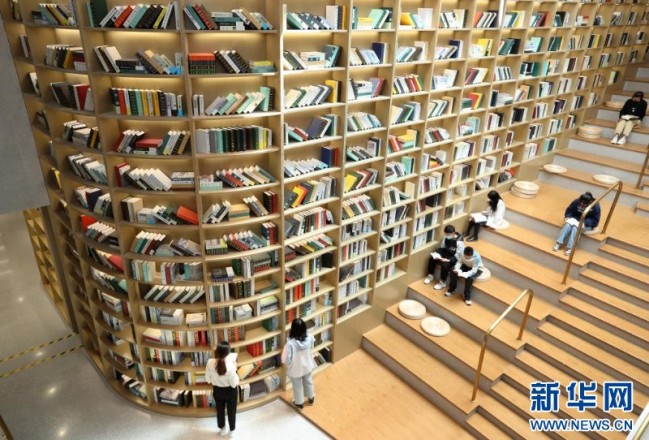 2021年5月2日，读者在安徽省蒙城县图书馆天梯书架旁阅读书籍。新华社发（胡卫国 摄）