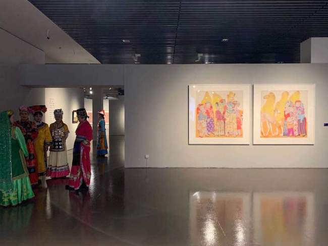 展览现场，马小娟的《高原红》与一旁身穿民族服饰的人