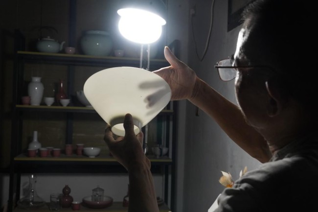 熊国安在检验一只薄胎碗的厚度（7月14日 新华社记者 周密 摄）。