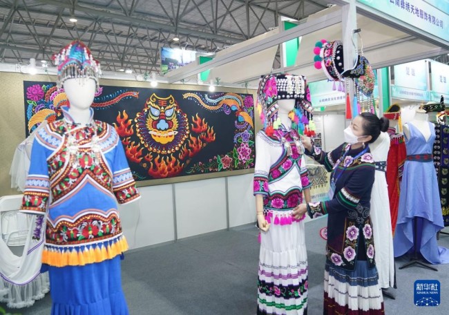 10月27日，商家在创意云南2021文化产业博览会上整理民族服饰。
