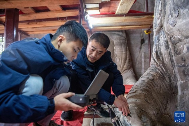　　11月12日，修缮工程现场技术员寻执政（左）、邵明贵在对造像进行表面弹性波检测。新华社记者 唐奕 摄