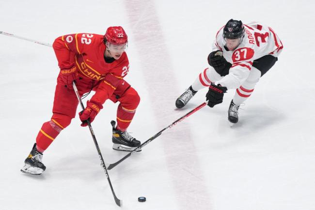 2月13日,在国家体育馆举行的北京2022年冬奥会男子冰球小组赛中,中国队迎战加拿大队。图为来自昆仑鸿星冰球俱乐部的中国队球员福帅(左)在比赛中。新华社记者杜宇摄