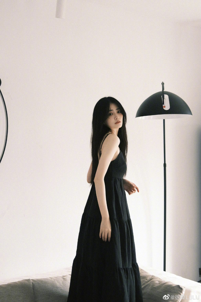 徐璐在个人社交平台晒出一组黑色连衣裙造型随拍,她披散长发在沙发上