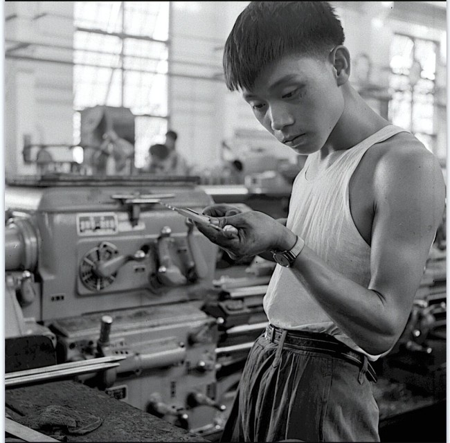 图为正在机械厂专心工作的小伙子。从他那专心致志的表情可以看出，他的生活平静又安宁。