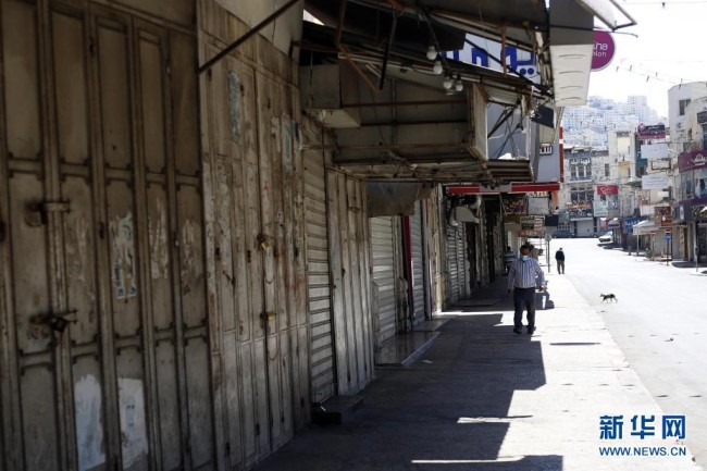  5月18日，人们经过约旦河西岸城市纳布卢斯街头关闭的店铺。 当日，约旦河西岸多个城市举行罢工，抗议以色列对加沙地带的空袭。