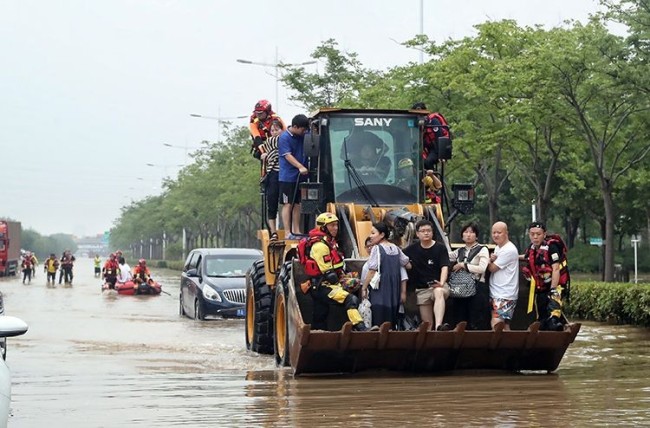 7月21日，郑州，金水东路东四环桥下被困群众乘坐挖掘机前往安全地带。