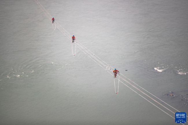 12月5日，在白鹤滩—江苏±800千伏特高压直流输电线路工程（重庆段）江津长江大跨越施工现场，工人在长江上空作业（无人机照片）。