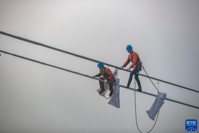 12月5日，在白鹤滩—江苏±800千伏特高压直流输电线路工程（重庆段）江津长江大跨越施工现场，工人在长江上空作业。