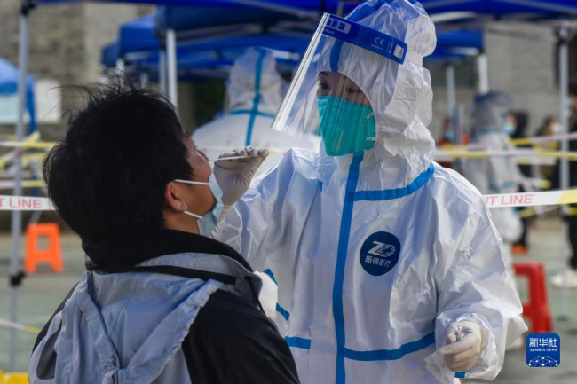 12月12日，浙江省宁波市镇海区医护人员在检测点给居民做核酸检测。