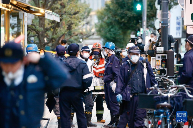 12月17日，救援人员聚集在..大阪发生火灾的楼房附近。