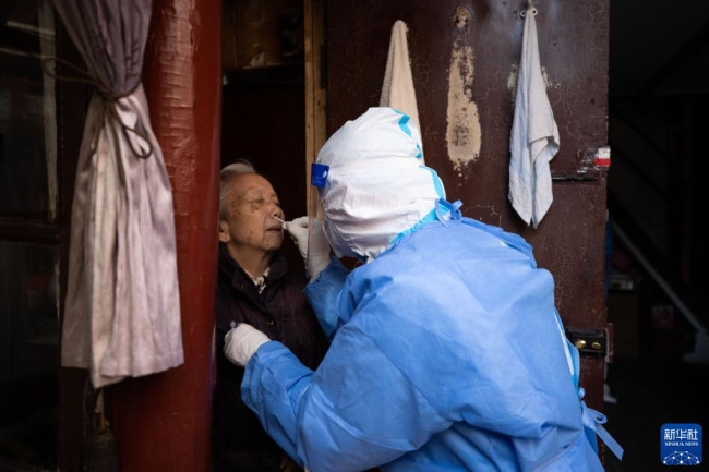4月3日，在上海市黄浦区豫园街道，工作人员帮助老人做抗原检测。