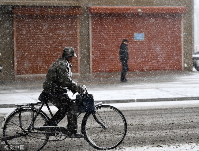 内蒙古呼伦贝尔四月飞雪 市民顶风冒雪保暖出行