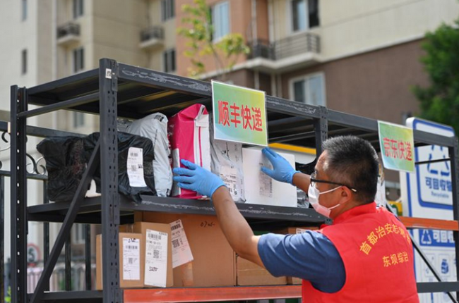 5月24日，北京朝阳区东坝乡东泽园社区东泽园一号院门口，工作人员分类摆放快递。