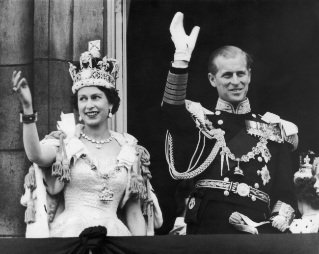 1953年6月2日，英国伦敦，英国女王伊丽莎白二世和丈夫菲利普亲王从白金汉宫的阳台上向人群挥手致意。