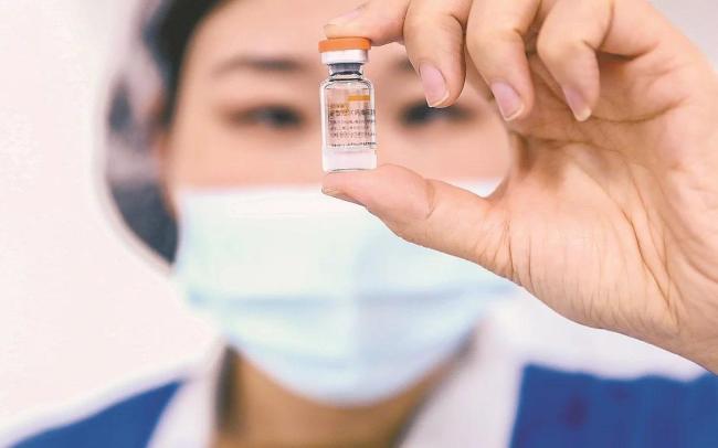 ▲2020年12月23日，科兴中维的工作人员在包装车间展示西林瓶包装新冠病毒灭活疫苗。 图/新华社