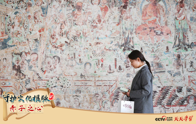 2023年4月25日，敦煌研究院文物数字化保护团队创意营销人员廖雪婷从一幅高保真复制壁画前走过。