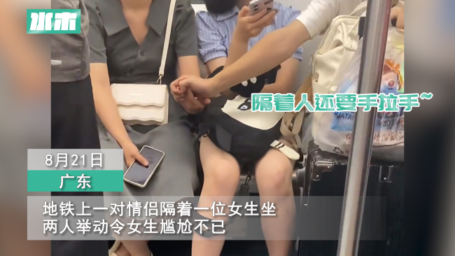 情侣地铁上隔人坐仍手拉手 坐在中间的女生尴尬埋头玩手机