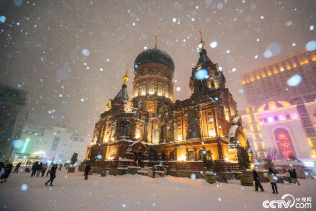 哈尔滨：教堂灯光与雪花相映成景