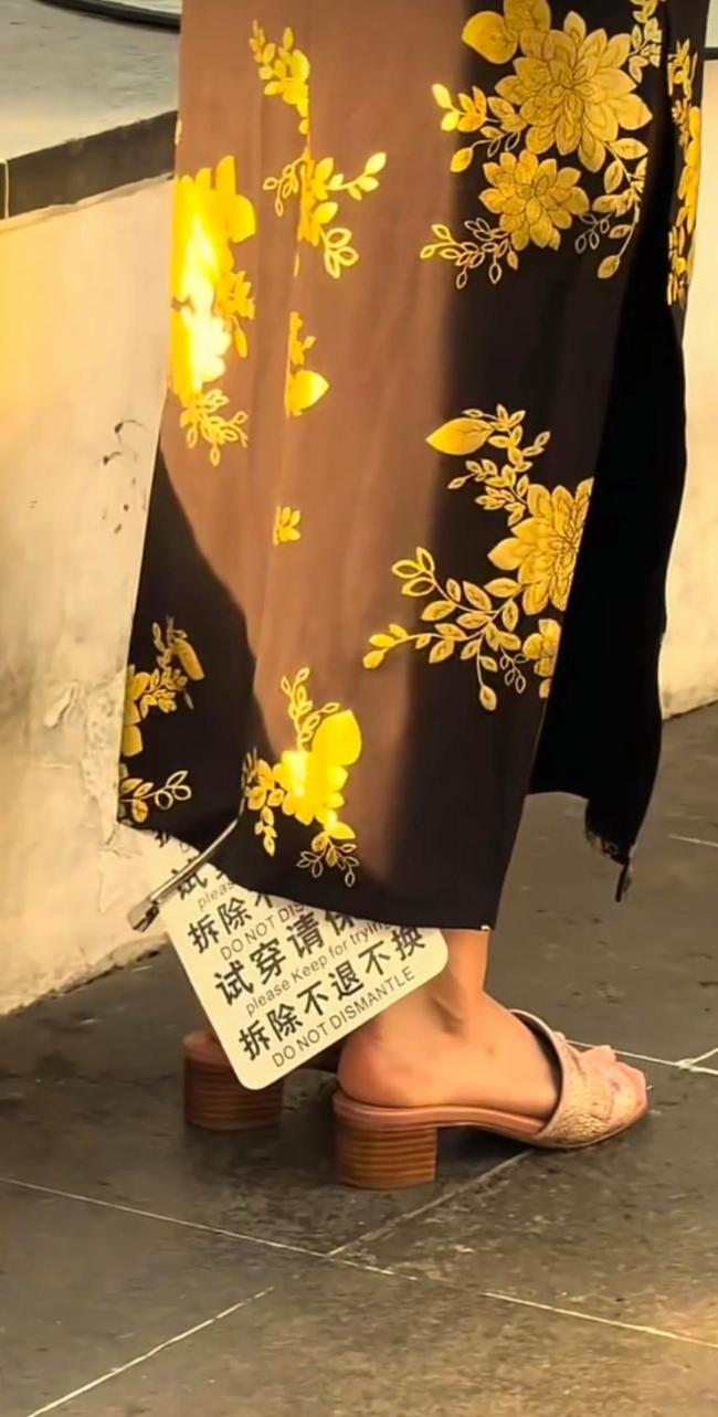 女子穿着带有巨大吊牌旗袍街头拍照