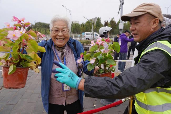北京上百位市民雨中排队 接国庆鲜 花香传递节日温情
